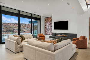 Living room with floor to ceiling windows, a premium fireplace, and recessed lighting