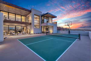 View of tennis court featuring a patio and a balcony