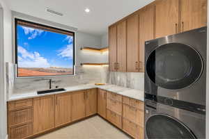Laundry room with cabinet space, stacked washer / dryer, recessed lighting, and light tile patterned flooring