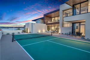 View of tennis court featuring a balcony and a patio