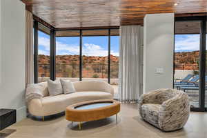 Sitting room with expansive windows, wooden ceiling, and a mountain view