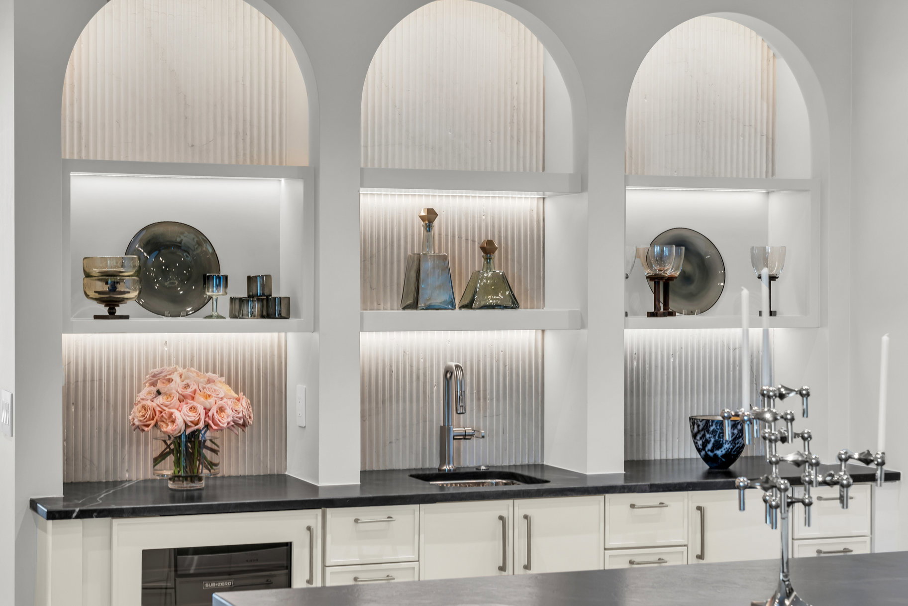 Detailed view of open shelves, beverage cooler, white cabinets, and dark stone counters