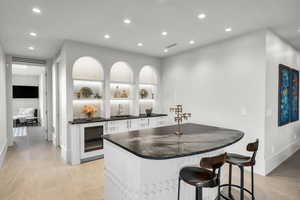 Kitchen featuring a breakfast bar area, white cabinetry, recessed lighting, wine cooler, and open shelves