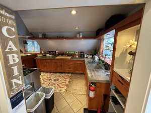 Kitchen with wood finish cabinets, light tile patterned floors, recessed lighting, light countertops, and vaulted ceiling
