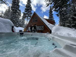 Snow covered rear of property featuring a hot tub
