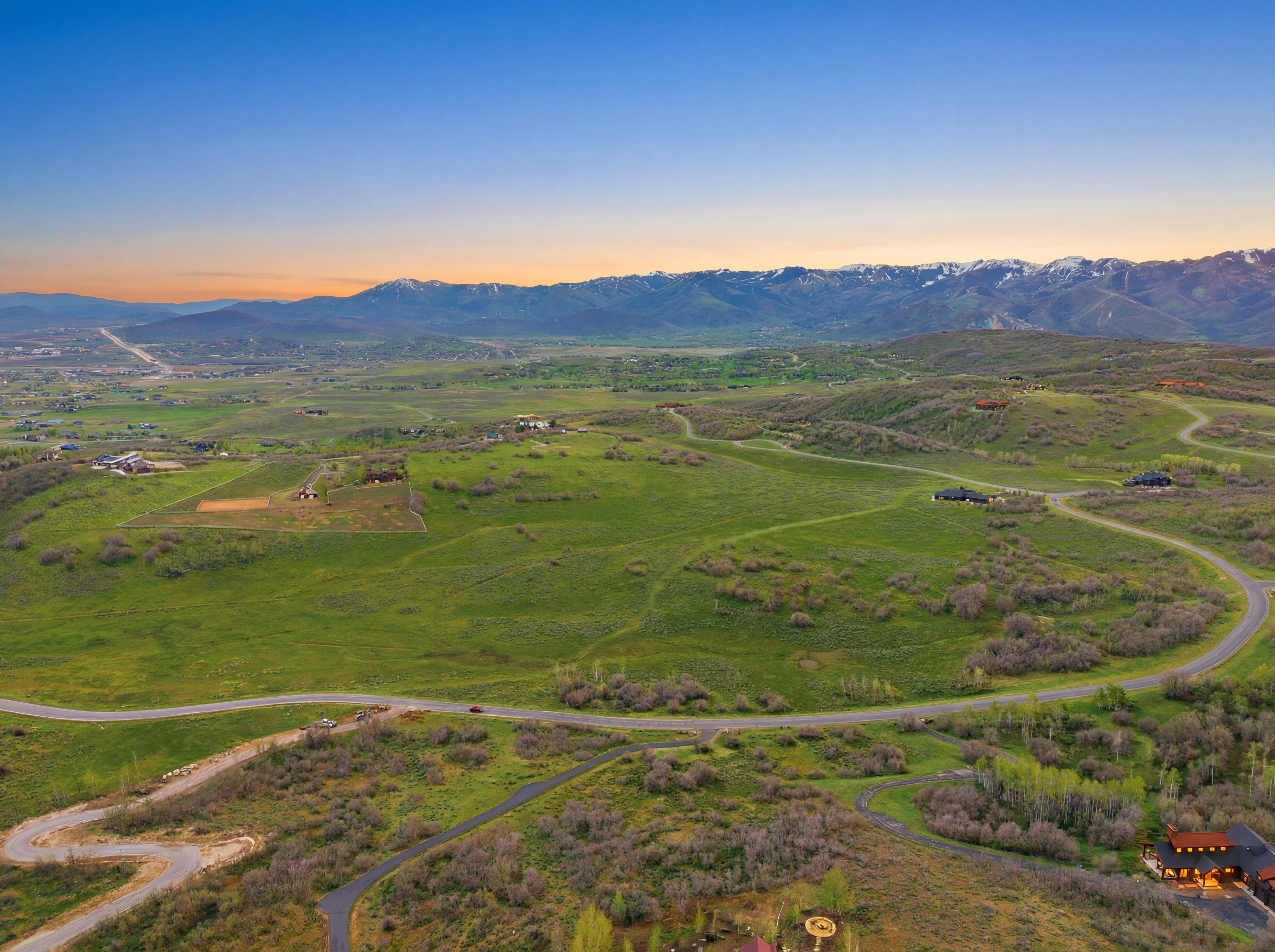 Expansive green landscapes featuring winding roads and distant mountain ranges with snow-capped peaks