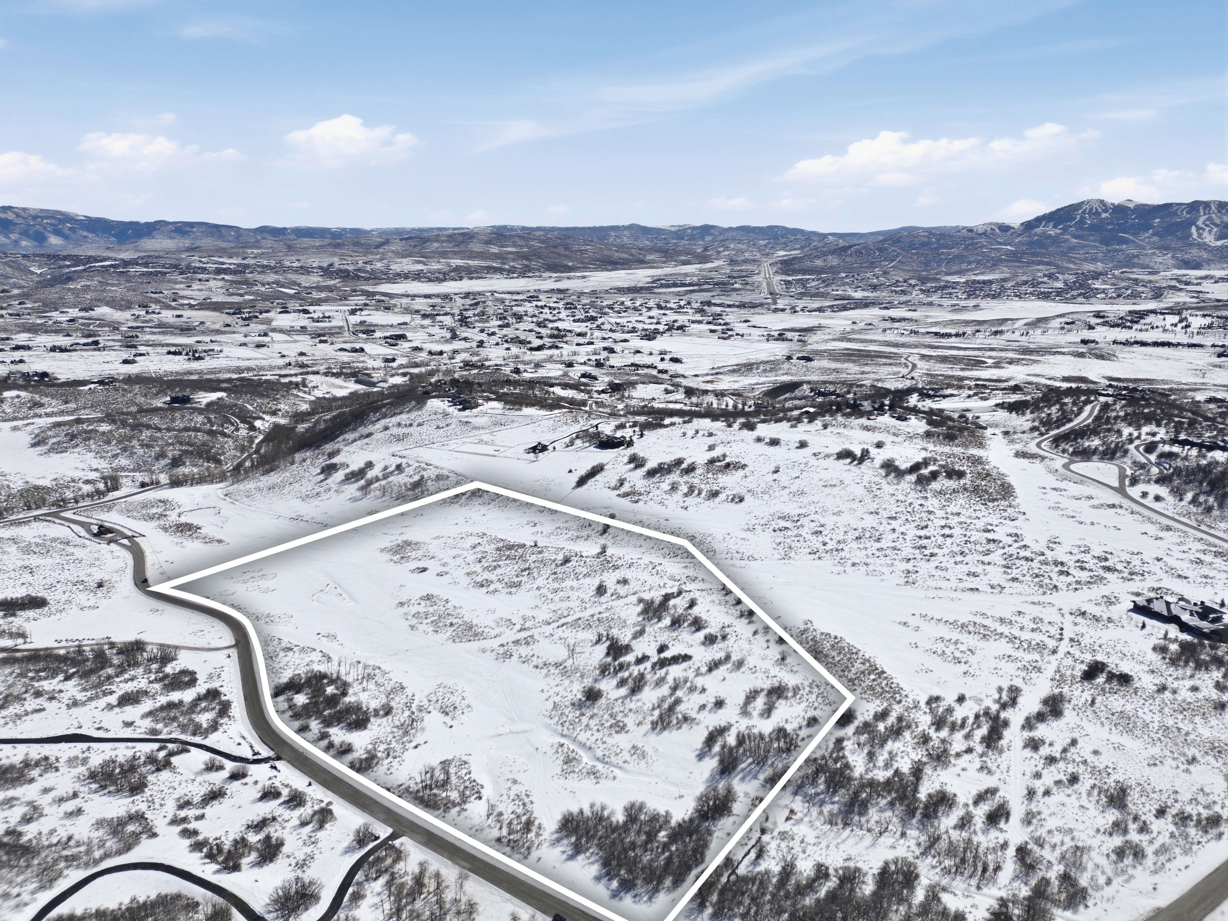 Snowy aerial view featuring a mountain view and property parcel outlined