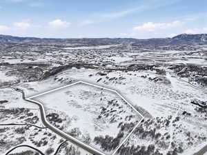 Snowy aerial view featuring a mountain view and property parcel outlined