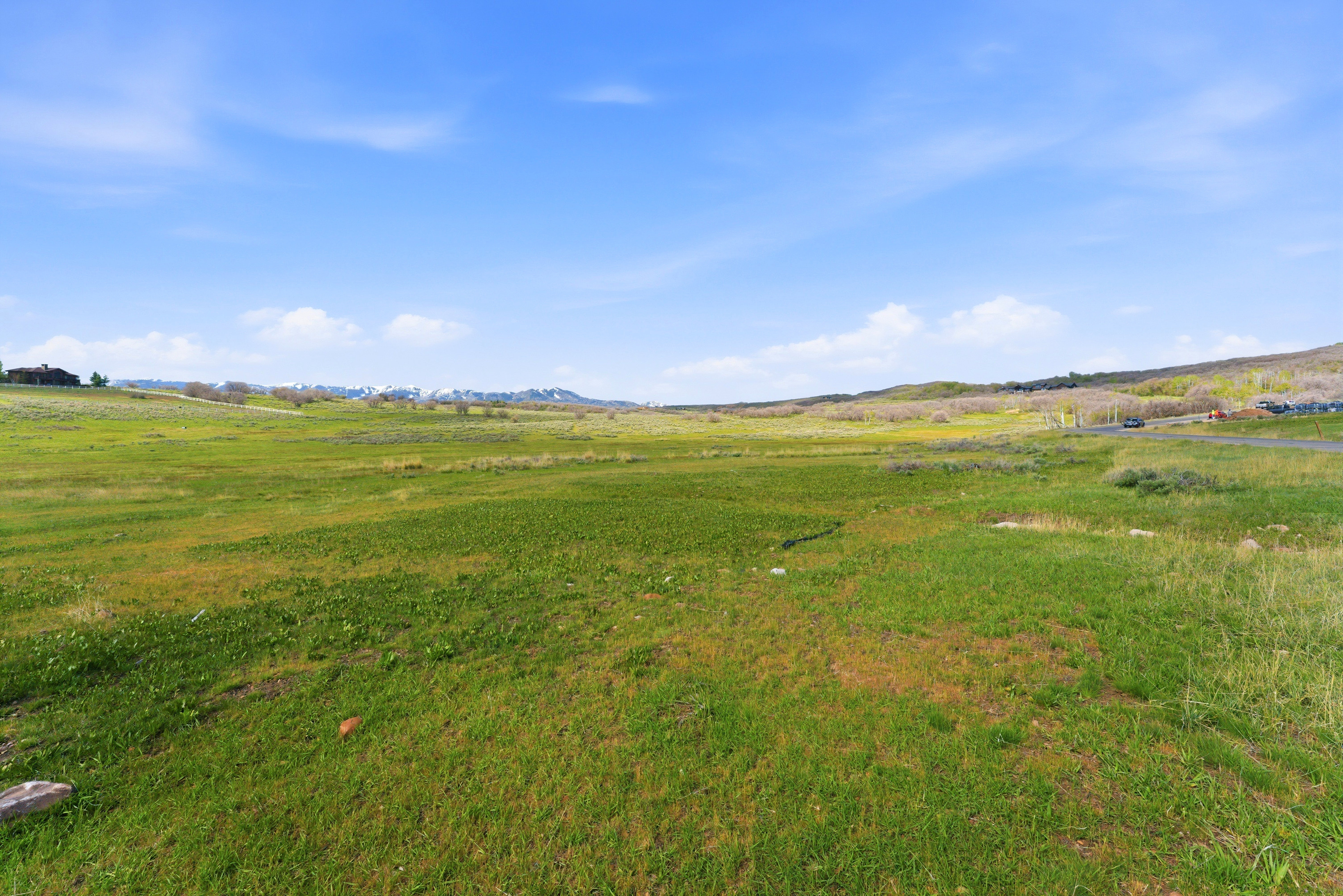 Expansive green landscape with distant rolling hills and a clear blue sky