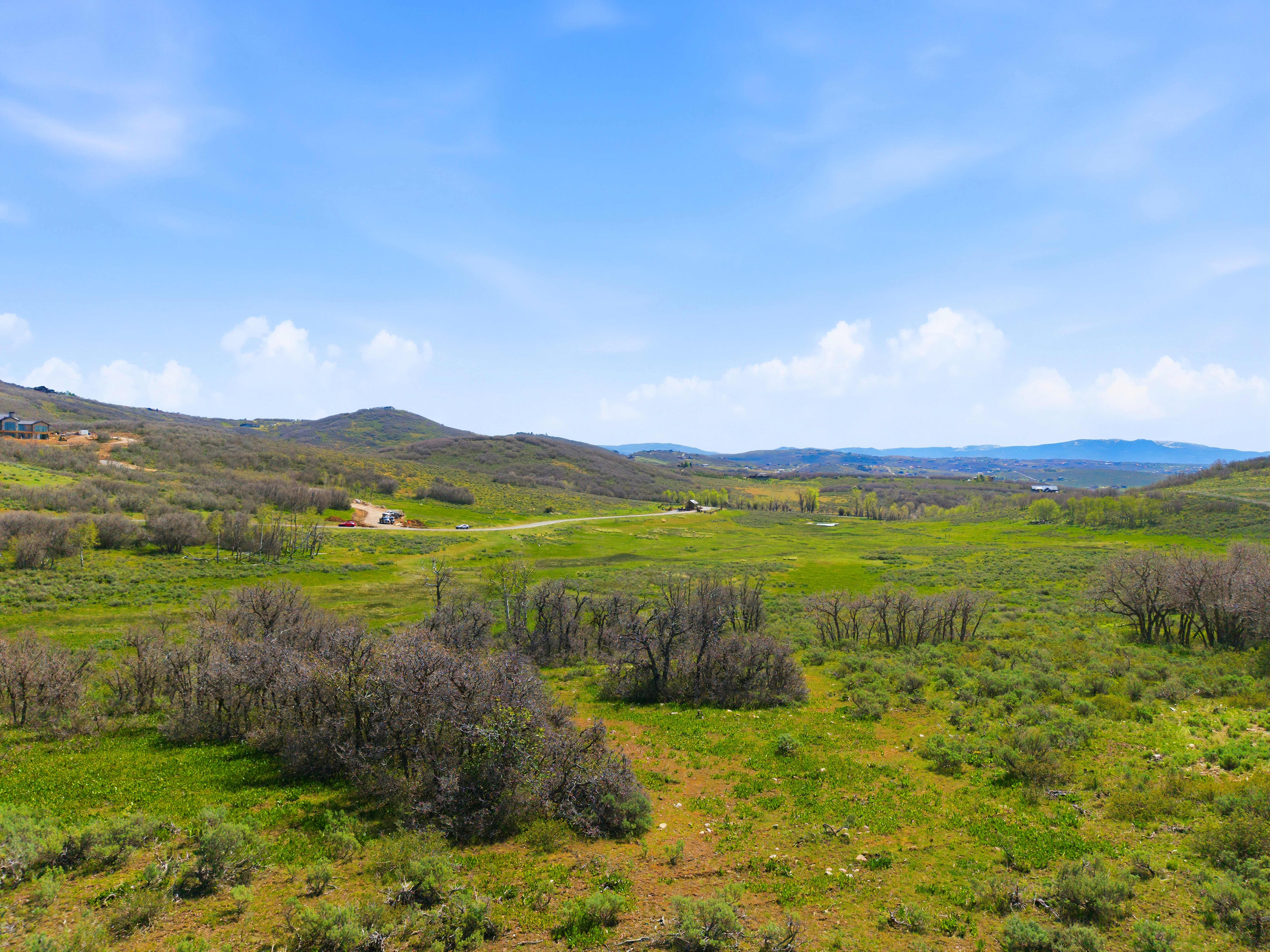 Expansive land parcel featuring rolling hills and distant mountainous terrain