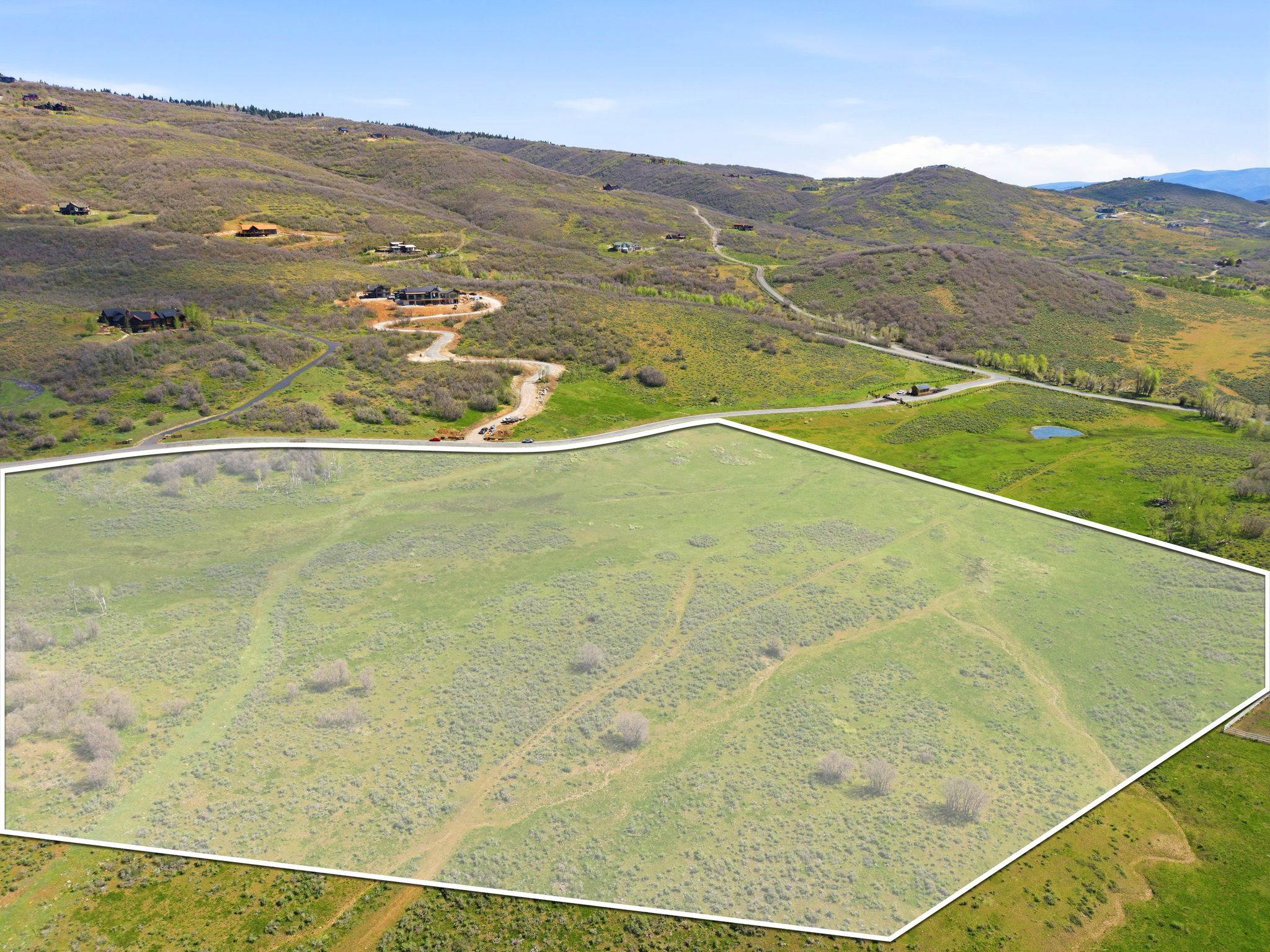 Expansive undeveloped land parcel with varied topography, bordered by roadways