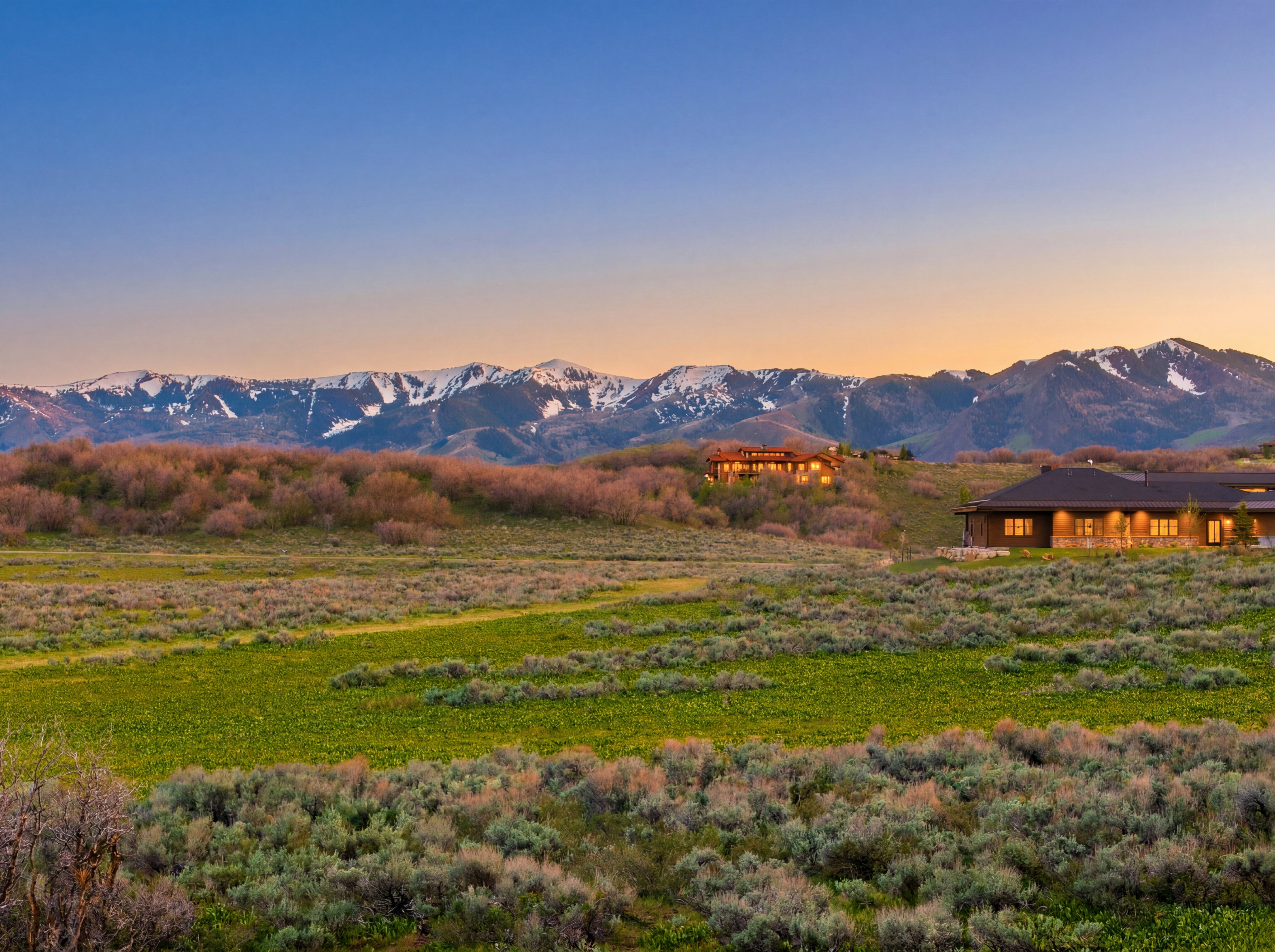 Expansive natural landscape featuring rolling hills and snow-capped mountains