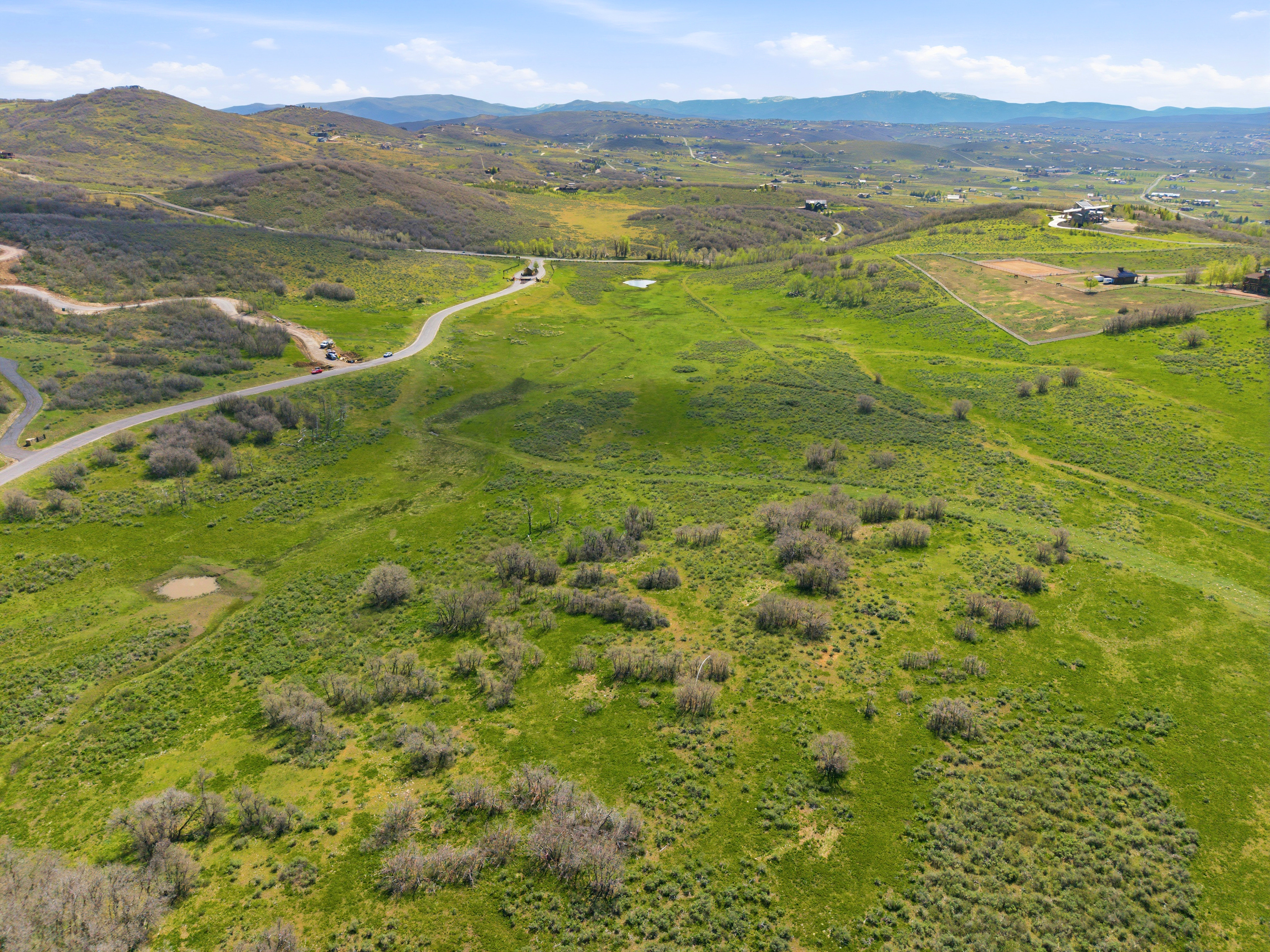 Expansive green landscape featuring rolling hills and scattered brush