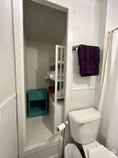 Bathroom featuring a shower with shower curtain and wainscoting