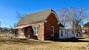 View of property exterior featuring brick siding and roof with shingles