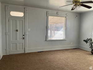 Carpeted entrance foyer with a ceiling fan and a textured wall