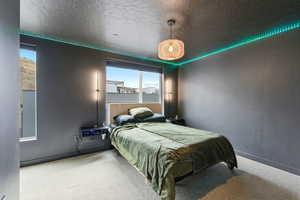 Carpeted bedroom featuring a textured ceiling and baseboards