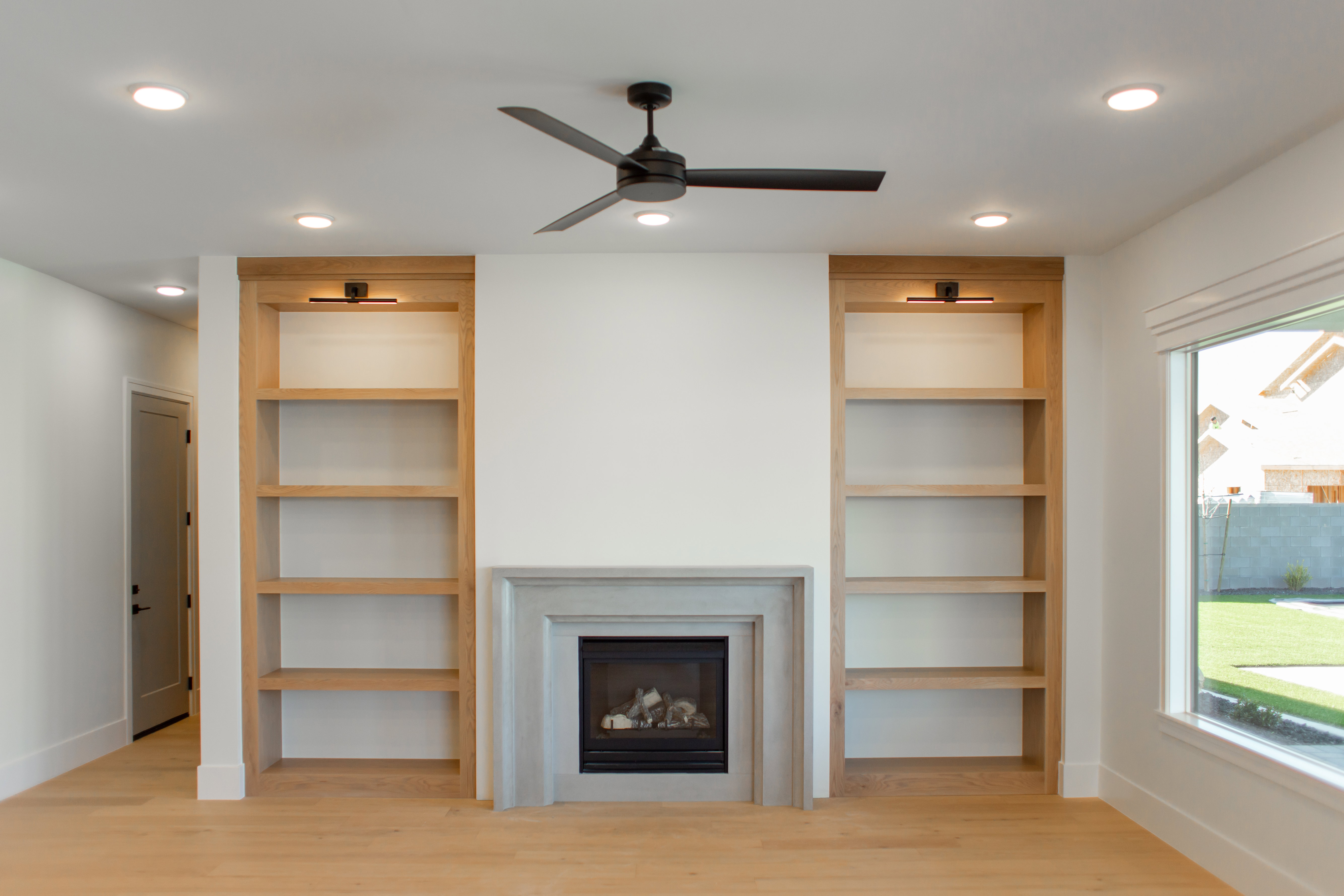 Unfurnished living room featuring recessed lighting, a glass covered fireplace, built in shelves, light wood-type flooring, and ceiling fan