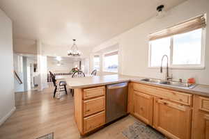 Kitchen with a peninsula, stainless steel dishwasher, light countertops, light wood-type flooring, and light wood finish cabinets