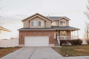 Traditional-style home featuring covered porch, a garage, driveway, brick siding, and stucco siding