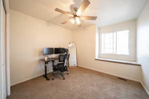 Carpeted office featuring baseboards and a ceiling fan