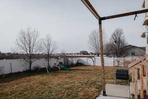 Fenced backyard featuring a playground