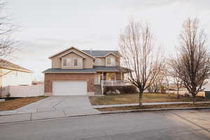 View of front of home featuring covered porch, a garage, concrete driveway, brick siding, and stucco siding