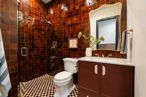 Full bath with tile walls, vanity, a stall shower, and backsplash