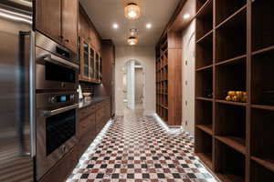 Kitchen featuring stainless steel appliances, dark countertops, arched walkways, light floors, and recessed lighting