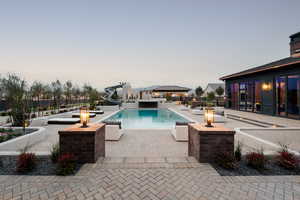 View of pool with a water slide, patio surround, a fenced backyard, and a jacuzzi