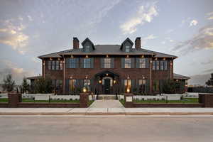 View of front facade with a chimney, brick siding, and a fenced front yard