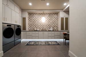 Laundry area featuring washer and clothes dryer, cabinet space, and recessed lighting