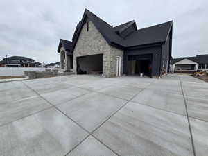 View of side of property featuring driveway, stone siding, and a garage