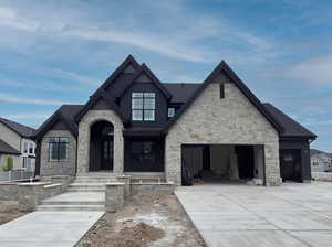View of front of property with stone siding, concrete driveway, and an attached garage