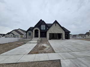 View of front of property featuring stone siding, concrete driveway, and a residential view