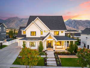 Modern inspired farmhouse with covered porch, a standing seam roof, board and batten siding, concrete driveway, and a mountain view