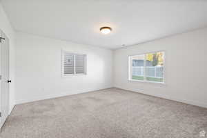 Spare room featuring light colored carpet and baseboards