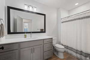 Full bathroom with vanity, dark wood finished floors, and recessed lighting