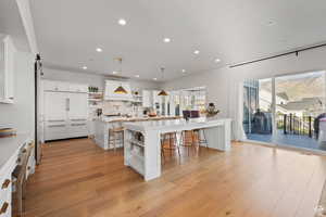 Kitchen with open shelves, a breakfast bar, pendant lighting, white cabinets, and light wood-style floors
