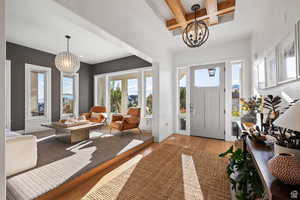 Foyer entrance with wood-type flooring, coffered ceiling, and suspended lighting