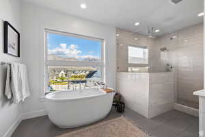 Bathroom featuring a freestanding tub, walk in shower, tile patterned floors, recessed lighting, and vanity