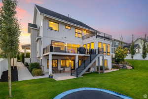 Back of house at dusk with a patio, board and batten siding, and a shingled roof