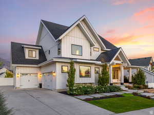 Modern farmhouse style home with board and batten siding, roof with shingles, and concrete driveway