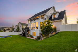 Back of house at dusk with a fenced backyard, board and batten siding, and a wooden deck