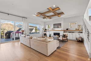 Living room with coffered ceiling, light wood-style flooring, a brick fireplace, and recessed lighting