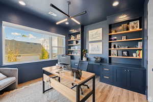 Office space featuring built in shelves, light wood-type flooring, ceiling fan, and recessed lighting
