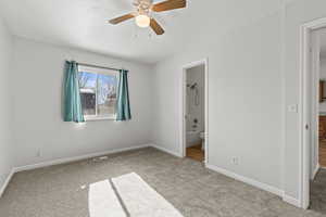 Unfurnished bedroom featuring carpet flooring, ensuite bath, and ceiling fan