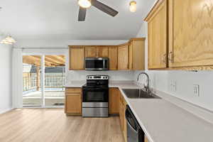 Kitchen with stainless steel appliances, light countertops, a ceiling fan, light wood-style flooring, and pendant lighting