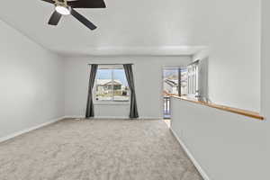 Empty room featuring light carpet, ceiling fan, and a textured ceiling