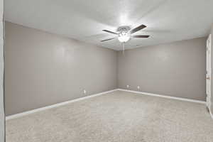 Carpeted empty room featuring a textured ceiling and a ceiling fan